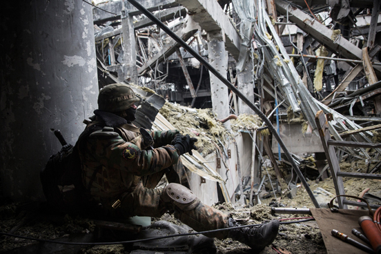 Um rebelde pró-Rússia descansa enquanto monitora soldados ucranianos prisioneiros de guerra que foram forçados a buscar por corpos no meio dos destroços do aeroporto. (Foto: Andrew Burton / Getty Images)