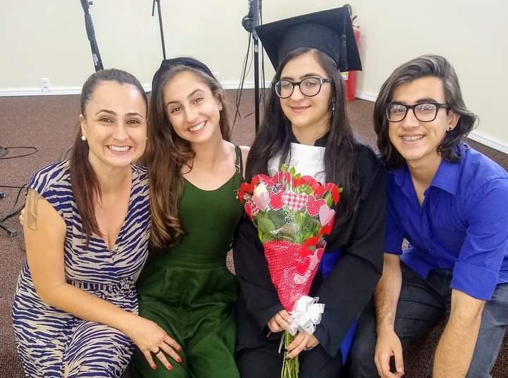Danielle sentada ao lado dos três filhos durante a formatura da filha Mariana