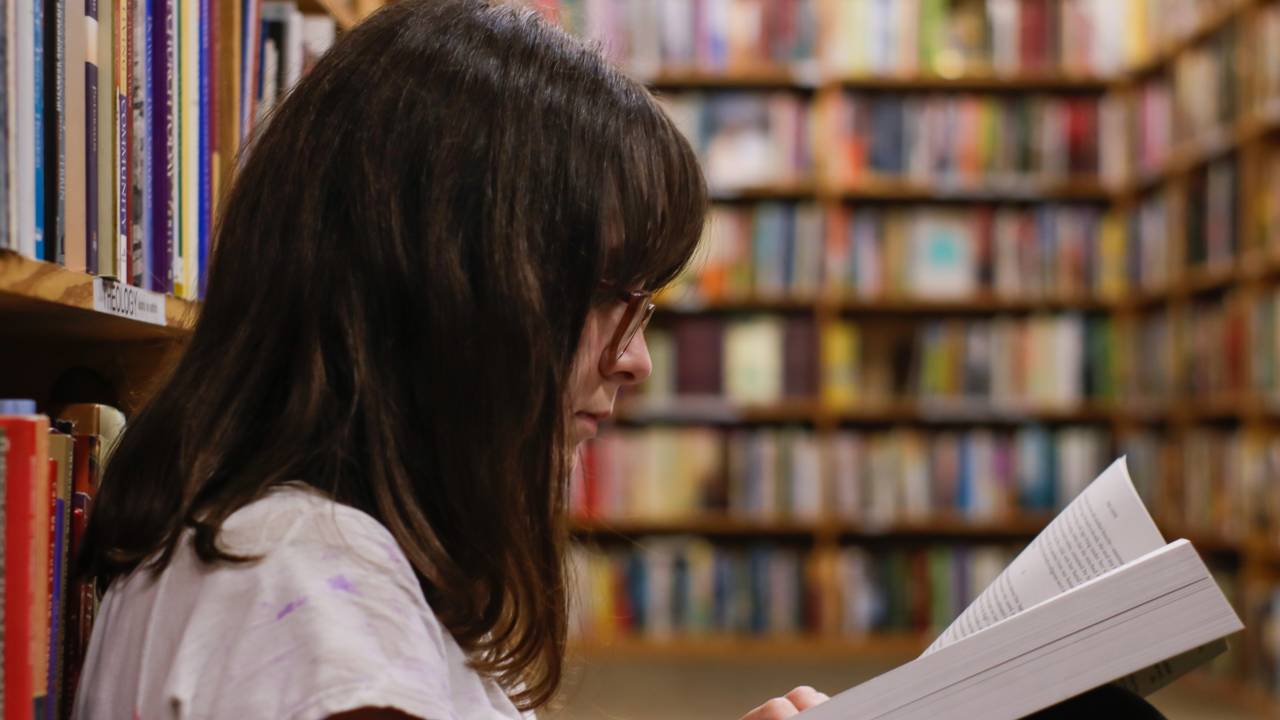 estudante lendo um livro em uma biblioteca