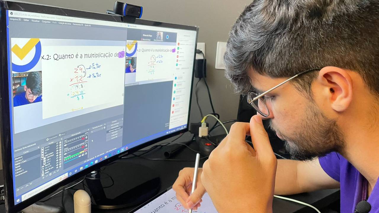Jovem estuda com cursinho online de Matemática no computador e tablet