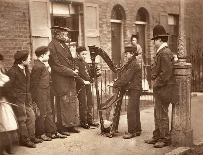 Londres-1870 Jovens na rua de Londres de 1870 tocam uma harpa.