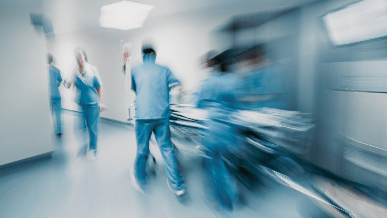 Cena de equipe médica levando uma maca hospitalar por um hospital