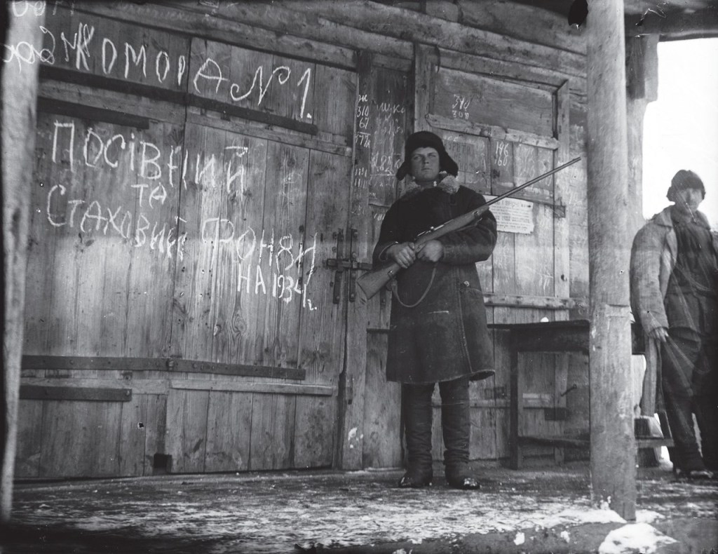 Um membro armado do Komsomol, a organização juvenil do Partido Comunista da União Soviética, protege um celeiro com grãos. Conhecido como Holodomor, o genocídio praticado contra os ucranianos matou milhares de fome