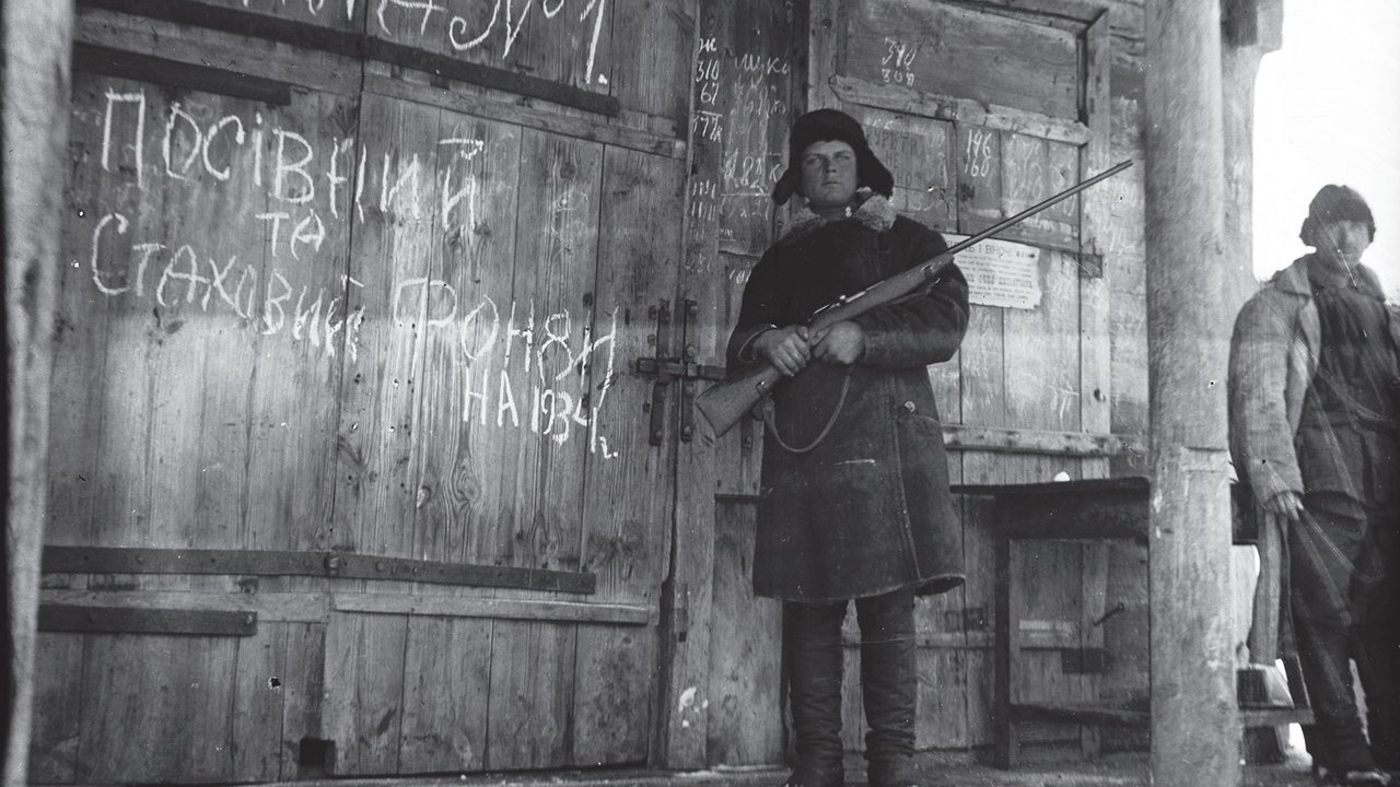 Um membro armado do Komsomol, a organização juvenil do Partido Comunista da União Soviética, protege um celeiro com grãos. Conhecido como Holodomor, o genocídio praticado contra os ucranianos matou milhares de fome