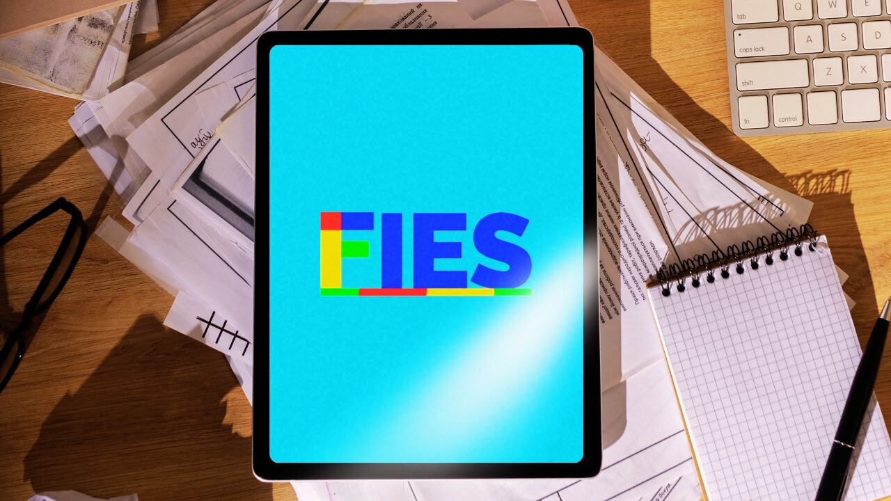 Montagem com tablet mostrando logo do Fies, em cima de mesa com papelada