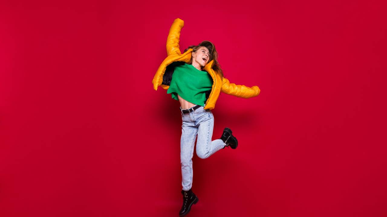 Mulher dançando, se mexendo, se divertindo, pulando em fundo vermelho