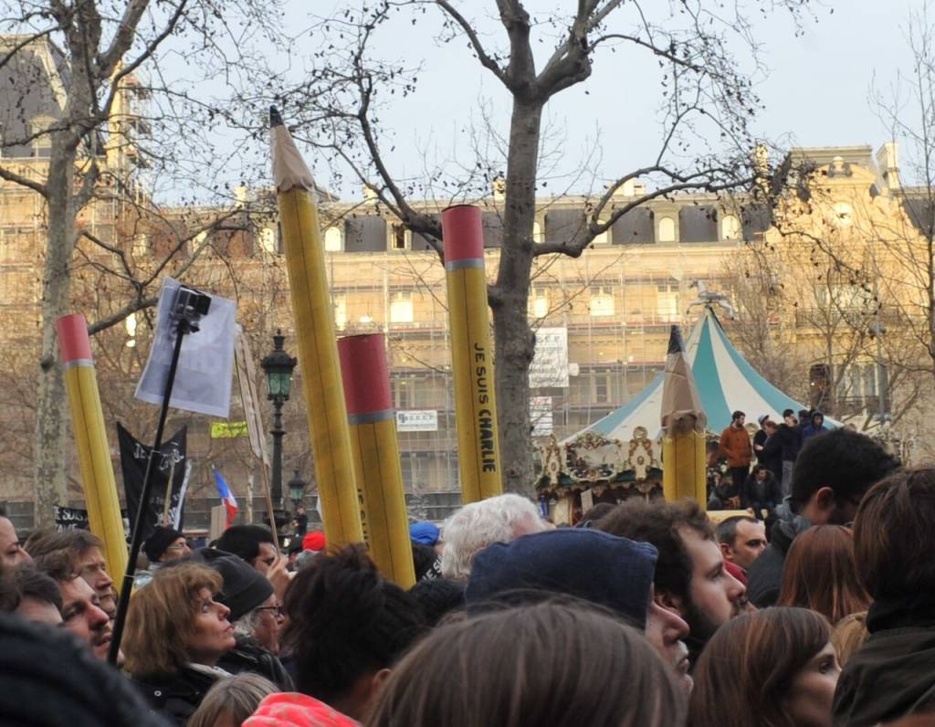 charlie-hebdo Civis marcham em Paris segurando bastões no formato de lápis de escrever, escrito