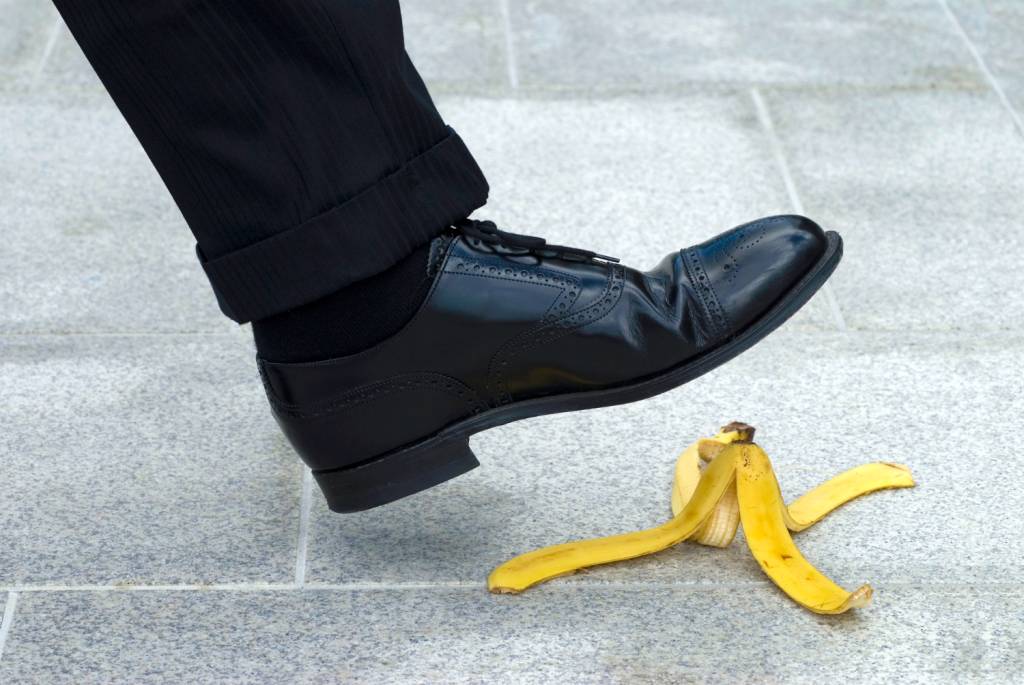 tropecar Pé em sapato masculino prestes a pisar em uma casca de banana