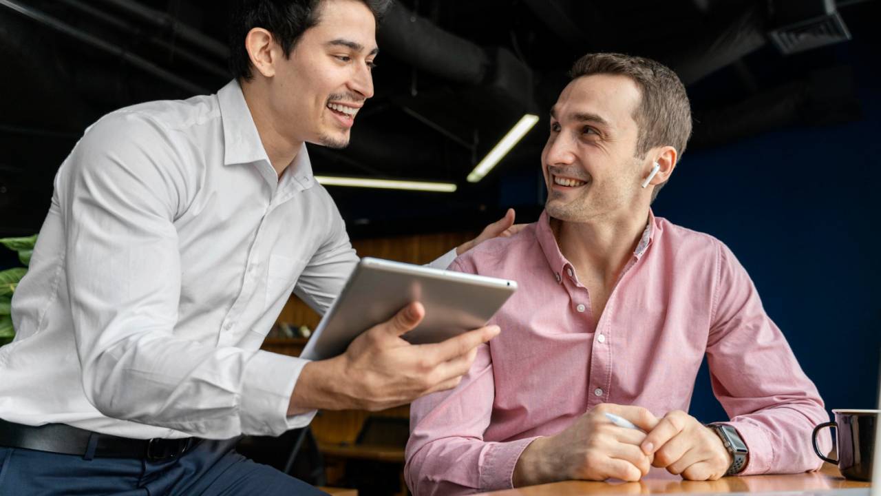 Dois homens conversando em mesa de ambiente corporativo